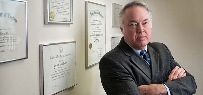 Photo shows an attorney with arms crossed and a confident look in front of a wall of law degrees.