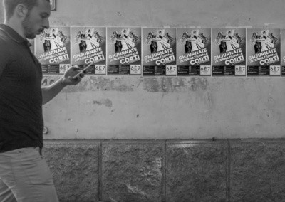 Photo shows a man walking past a wall of repeating advertisements as if trying to get his attention while he looks at his mobile phone.