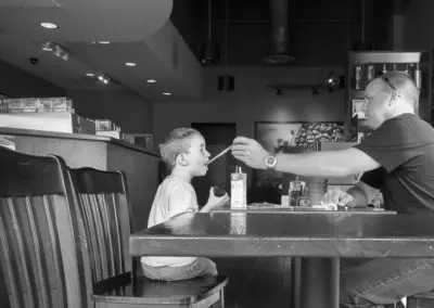 Photo of a young boy getting a tase of dads coffee beverage at a local coffee shop.